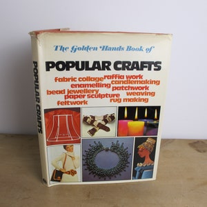 May include: The Golden Hands Book of Popular Crafts book cover features a collage of images showcasing various crafts, including fabric collage, raffia work, candlemaking, enamelling, patchwork, bead jewellery, paper sculpture, weaving, rug making, and feltwork.