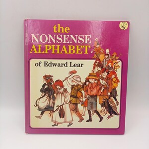 May include: A vintage hardcover book titled "the NONSENSE ALPHABET" by Edward Lear. The cover is a vibrant magenta with yellow text. The book's illustration features a group of children in period clothing.