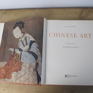 May include: A book titled "Chinese Art" by Lubor Hajek with photographs by Werner Forman. The cover features a painting of a woman in traditional Chinese clothing.