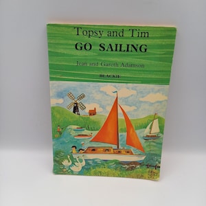 May include: A vintage children's book titled "Topsy and Tim Go Sailing" by Jean and Gareth Adamson. The cover shows a colourful illustration of a sailboat with an orange sail, swans, and a windmill. Published by Blackie.