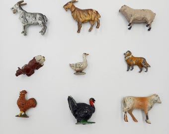 May include: Nine small, vintage farm animal figurines. The collection includes a goat, sheep, cow, dog, goose, rooster, and turkey. The figurines are painted in various colors, including brown, white, black, and orange.