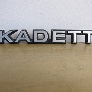 Vintage car badge. KADETT. Cool font! Classic car emblem badge silver script
