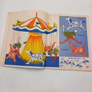 Op de afbeelding: Illustratie uit een open boek met een carrousel met dierenfiguren en een blauwe achtergrond. De carrousel heeft een rood, oranje en wit gestreept dak. De rechterpagina toont dierillustraties met de labels "Neddy", "Oswald" en "Jumbo".