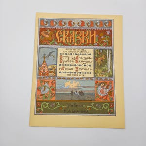 Op de afbeelding: Een vintage boekomslag met de titel "SKAZKI" in sierlijke letters. De omslag bevat illustraties en tekst in een vreemde taal, met decoratieve randen in oranje, groen en goud. Het boek staat op een crèmekleurige achtergrond.