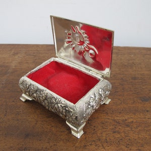 Vintage Schmuck- oder Schmuckschatulle. Gefüttert mit rotem Stoff. Silberfarbenes Metall mit verschnörkeltem Blüten- und Blattdekor.