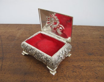 Vintage trinket or jewelry box. Lined with red fabric. Silvertone metal with ornate floral and leaf decoration.