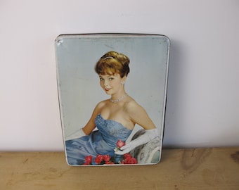 Vintage tin. 'Sitting Pretty' glamourous woman in evening dress with red roses. Rectangular biscuit tin