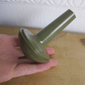 May include: A green plastic watering can nozzle with a round base and a long, thin spout.