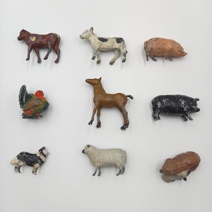 May include: A selection of nine miniature farm animal figures, painted in various colours. The set includes a cow, horse, pig, sheep, chicken, and a dog. The figurines are painted in shades of brown, white, black, and orange.