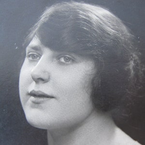 Antike fotografische Postkarte. Seltsam dreinblickende Dame. Schwarz-weiß Fotografie - echte Fotopostkarte