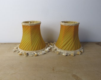 Pair of vintage gold fabric lampshades with braid tassle trim. Clip on lampshades.