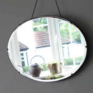 Oval art déco-spegel med dekorativ fasad. Klar att hängas på lång original synlig kedja.