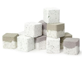 May include: A collection of square, decorative blocks. The blocks are white with speckled patterns and a gray band on the top. The blocks are stacked in a pile, showcasing their geometric design and color contrast.