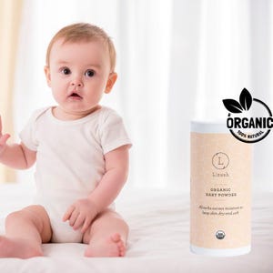 May include: A white container of organic baby powder with a green organic label. The label says "Lizush Organic Baby Powder" and "Absorbs excess moisture to keep skin dry and soft".