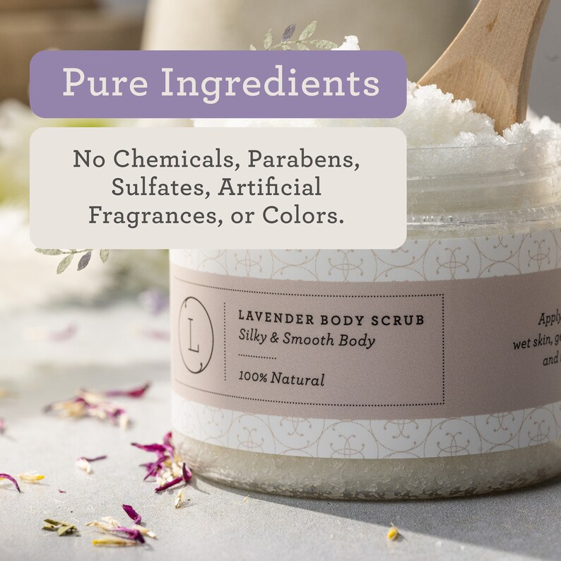 May include: A glass jar of lavender body scrub with a white label that reads "Lavender Body Scrub Silky & Smooth Body 100% Natural". The jar is filled with white sugar crystals and is sitting on a table with dried flower petals.
