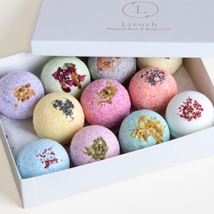 May include: A white box with the text "Lizush Natural Bath & Body Care" on the lid. The box is open and contains 10 colorful bath bombs with various ingredients visible.