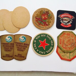 May include: A selection of vintage beer mats in different shapes and designs. Includes round, oval, and square mats with brewery logos and text. Some feature names like Lowenbrau and Brakspaer, and slogans such as "There's More to Breaker Than You Think!"