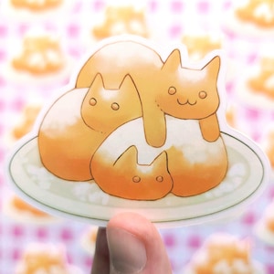 May include: A sticker featuring a cartoon illustration of three orange cats stacked on top of each other on a white plate. The cats are drawn in a simple, rounded style with big eyes and small mouths. The sticker is perfect for adding a touch of whimsy to any surface.
