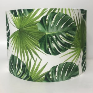 May include: A white lampshade with a tropical leaf pattern. The leaves are green and have a realistic look.