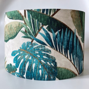 May include: A white lampshade featuring a tropical leaf design in shades of green and blue. The leaves are stylised and have a textured appearance.