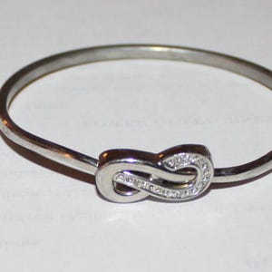 May include: A white ceramic mug with a black handle and the text "But First, Coffee" in a bold, black font. The mug is set against a neutral background, highlighting its simple design.