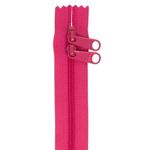 May include: A bright pink double-pull zipper against a white background. The zipper has two pulls, and the teeth are visible along the length of the zipper. The zipper is made of fabric and metal.