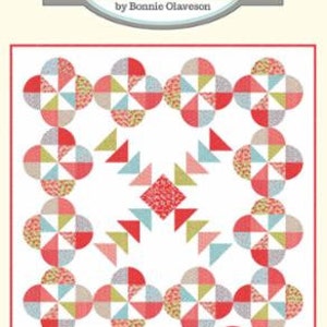 May include: A quilt pattern called "Ruby Bloom" by Cotton Way, designed by Bonnie Olaveson. The pattern features a red, white, and blue color scheme with a geometric design. The pattern is labeled as "Layer Cake Friendly!" and has the number #988.