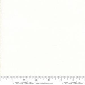 May include: A plain white fabric with a subtle texture. The fabric is shown with a ruler for scale.