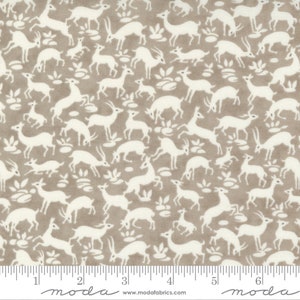 May include: A beige fabric with a white repeating pattern of stylized deer. The fabric has a ruler with inches marked on it.