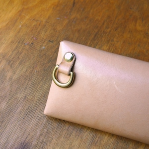 May include: A light beige leather case with a gold metal loop and a snap closure.