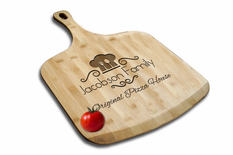 May include: A personalized bamboo pizza peel with a chef hat and utensils design. The text "Jacobson Family Original Pizza House" is engraved on the peel.