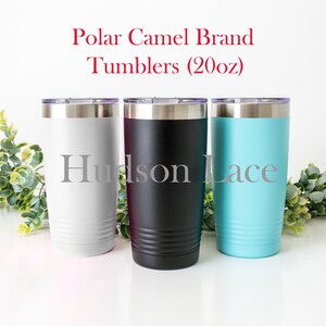 K&ouml;nnte beinhalten: Drei Edelstahlbecher, einer grau, einer schwarz und einer hellblau, mit einem silbernen Deckel. Die Becher sind mit "Polar Camel Brand Tumblers (20oz)" beschriftet.