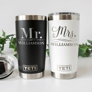 K&ouml;nnte beinhalten: Zwei YETI Becher aus Edelstahl mit Deckel. Der schwarze Becher ist mit "Mr. Williamson" graviert. Der wei&szlig;e Becher ist mit "Mrs. Williamson" graviert.