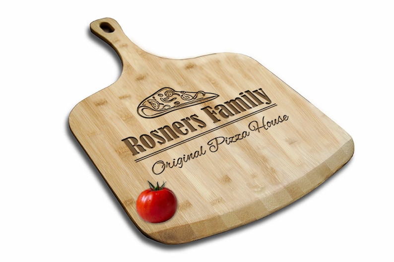 May include: A wooden pizza peel with a handle, engraved with the text "Rosners Family Original Pizza House" and a pizza slice graphic. A red tomato sits on the peel.