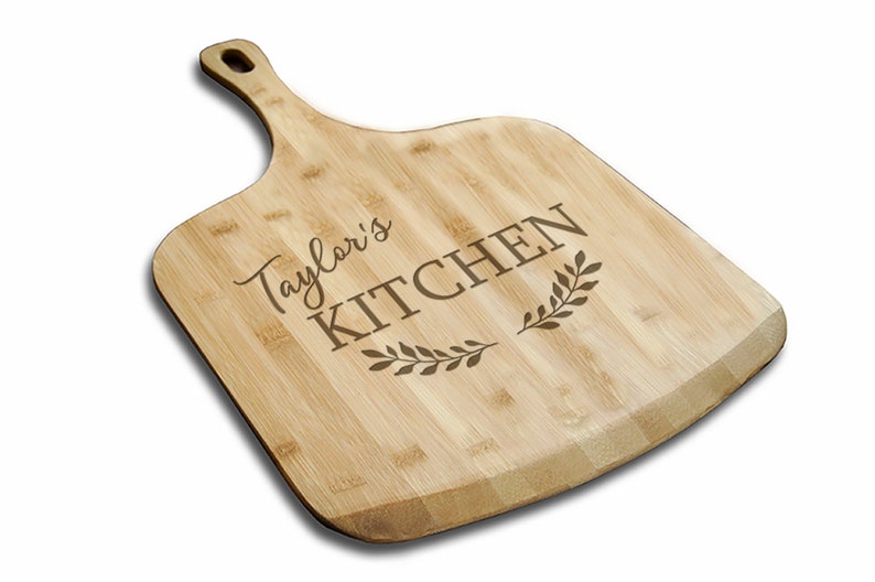 May include: A personalized bamboo cutting board with the text "Taylor's Kitchen" and a decorative leaf design.