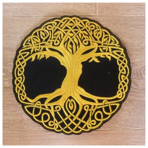 Può includere: Una toppa ricamata circolare con un design a forma di albero della vita celtico dorato su sfondo nero.