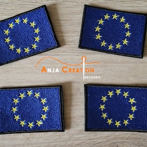 Op de afbeelding: Vier geborduurde patches van de vlag van de Europese Unie. Elke patch heeft een blauwe achtergrond met een cirkel van 12 gele sterren.
