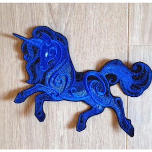 Peut inclure: Patch brodé d'une licorne bleue avec des détails complexes. La licorne est debout sur ses pattes arrière, la tête tournée sur le côté. Le patch est fait d'un tissu doux et velouté.