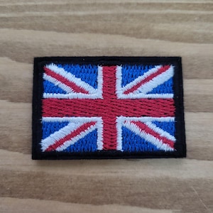 Könnte beinhalten: Gestickter Aufnäher mit dem Union Jack, der Flagge des Vereinigten Königreichs. Der Aufnäher hat einen schwarzen Rand, einen blauen Hintergrund und ein rot-weißes Kreuzmuster. Der Aufnäher ist rechteckig.