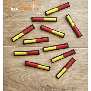 Peut inclure: Dix patchs thermocollants brodés jaunes et rouges. Les patchs sont rectangulaires et ont un contour noir. Les patchs sont disposés de manière dispersée sur une surface en bois.