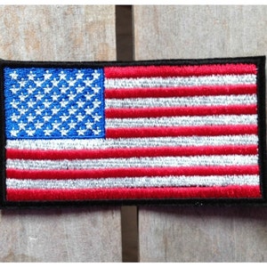 Peut inclure: Un petit patch brodé du drapeau américain avec des rayures rouges et blanches et des étoiles bleues sur un fond noir.