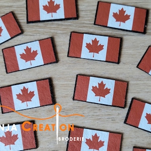 May include: A collection of ten small Canadian flag patches. The patches are made of felt and have a white background with a red maple leaf. The patches are surrounded by a black border.