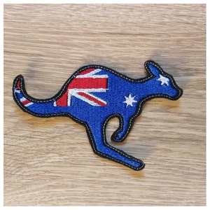 Può includere: Toppa ricamata a forma di canguro, raffigurante la bandiera australiana. Il canguro è blu con un bordo nero e cuciture bianche. Il design della bandiera include l'Union Jack, strisce rosse e stelle bianche.