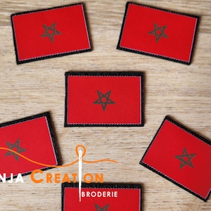 Op de afbeelding: Vijf rode geborduurde patches met een zwarte vijfpuntige ster met een cirkel erin. De patches hebben zwarte stiksels rond de randen.