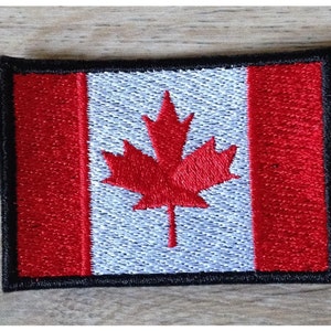 Op de afbeelding: Een geborduurde Canadese vlagpatch met een rood en wit ontwerp en een zwarte rand.