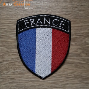Peut inclure: Patch brodé avec le drapeau français et le mot "FRANCE" en lettres blanches sur fond noir.