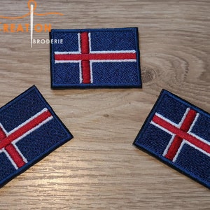 May include: Three embroidered patches of the Icelandic flag. The flag is blue with a white cross and a red cross inside the white cross.