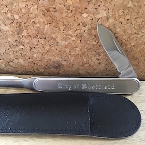 Escritorio/abridor de cartas con bolsa de cuero marcada como se muestra