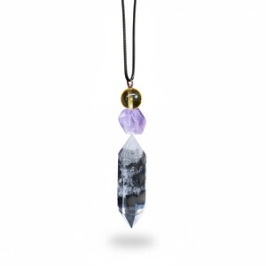 May include: A crystal pendant necklace featuring a clear quartz crystal point, a purple amethyst stone, and a yellow-green sphere. The pendant hangs from a black cord, creating a unique and eye-catching accessory.