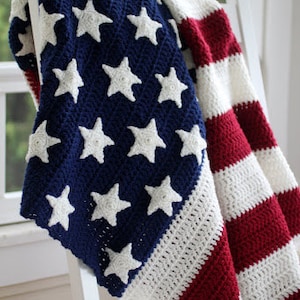 May include: A crocheted blanket in the colors of the American flag. The blanket is draped over a white rocking chair.